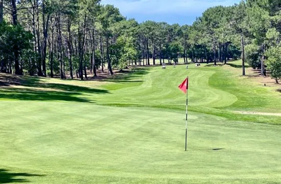 Les activités et loisirs autour de Lacanau. Golf de l'Ardilouse, Lacanau océan, à l'avant de la photo : le green avec le trou et le drapeau rouge. A l'arrière, le fairway bordé de pins maritimes
