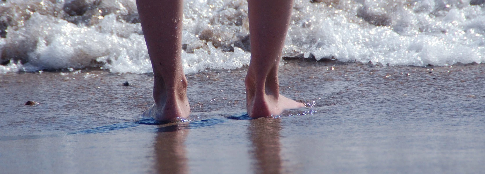La résidence les pieds dans le sable mouillé. Mouvement de l'eau, bouillon d'écume