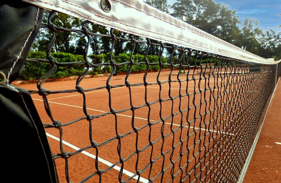 Les activités et loisirs autour de Lacanau. Filet d'un terrain de tennis sur un terrain de terre battue. A l'arrière un mur de végétation