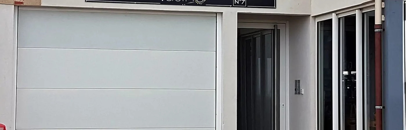 Entrée de la résidence à gauche le volet roulant pour accéder au parking à droite l'entrée piétonne et ses boites à clés