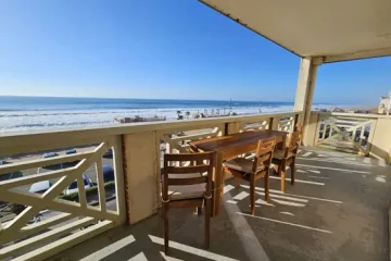 Appart Hôtel Pasino N°4, grande terrasse vue l'océan. Au loin la plage nord. Sur la terrasse une table en Tecks et ses 4 chaises