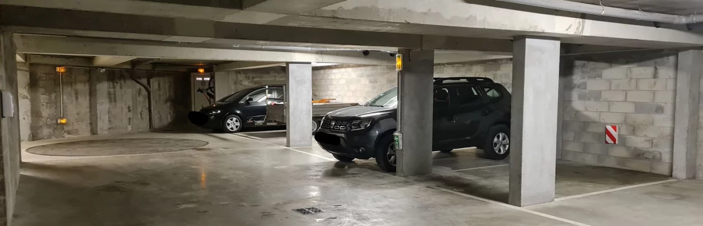 Le parking en sous-sol. Une place disponible par appartement. interdit aux véhicules over size. Au fond, la plateforme qui permet de se placer dans la bonne direction avant de se garer en marche arrière sur la place réservée pour chaque appartement