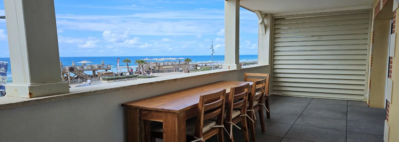 appart hôtel pasino n°3, grande terrasse équipée d'une table et ses chaises en teck. Depuis la terrasse vue sur le front de mer, La plage et l'océan.