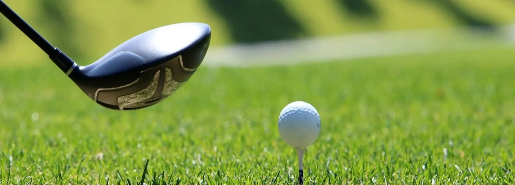 Les activités et loisirs autour de Lacanau. Une balle de golf sur un tee avec l'extrémité d'un driver qui s'apprête à la frapper sur une pelouse verte parfaite