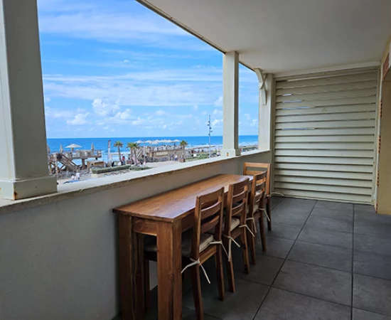 appart hôtel pasino n°3, grande terrasse équipée d'une table et ses chaises en teck. Depuis la terrasse vue sur le front de mer, La plage et l'océan.