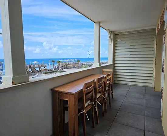 /appart hôtel pasino n°3, grande terrasse équipée d'une table et ses chaises en teck. Depuis la terrasse vue sur le front de mer, La plage et l'océan.