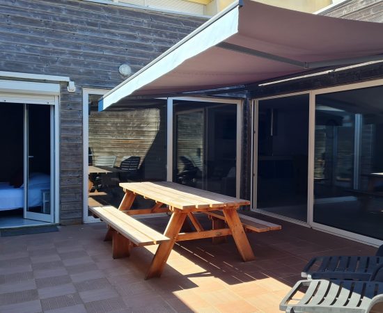 patio avec table pour repas et transats