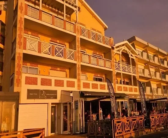 d'un soleil couchant. On voit les entrées de la residence Pasino et les restaurants qui sont en dessous